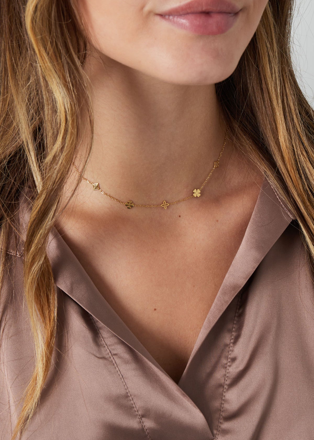 Model trägt Daisiana Necklace Gold mit filigranen Glückssymbolen aus vergoldetem Edelstahl