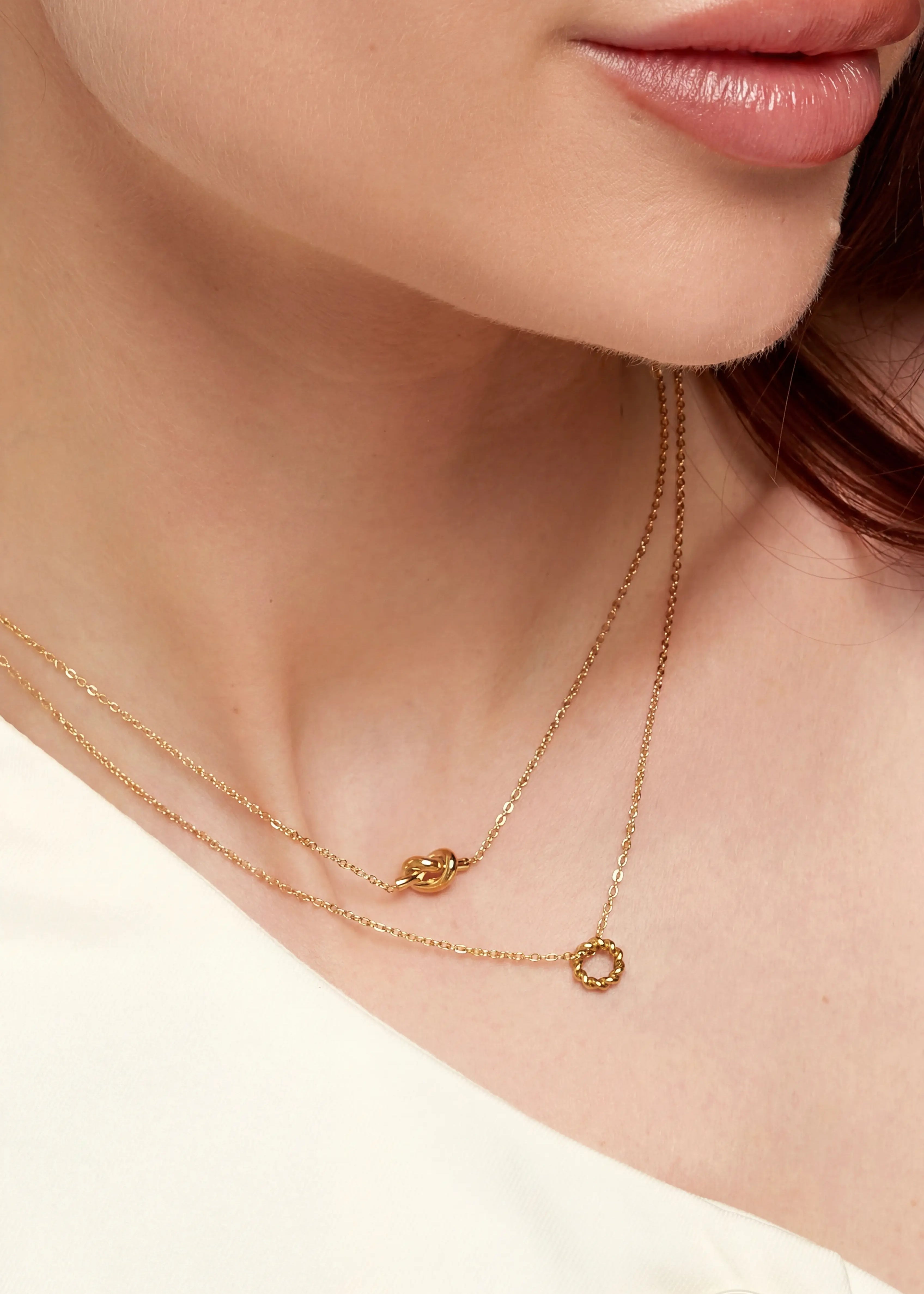 Frau trägt goldene Knoten Halskette aus vergoldetem Edelstahl von OLANA W. im minimalistischen Layering Look.