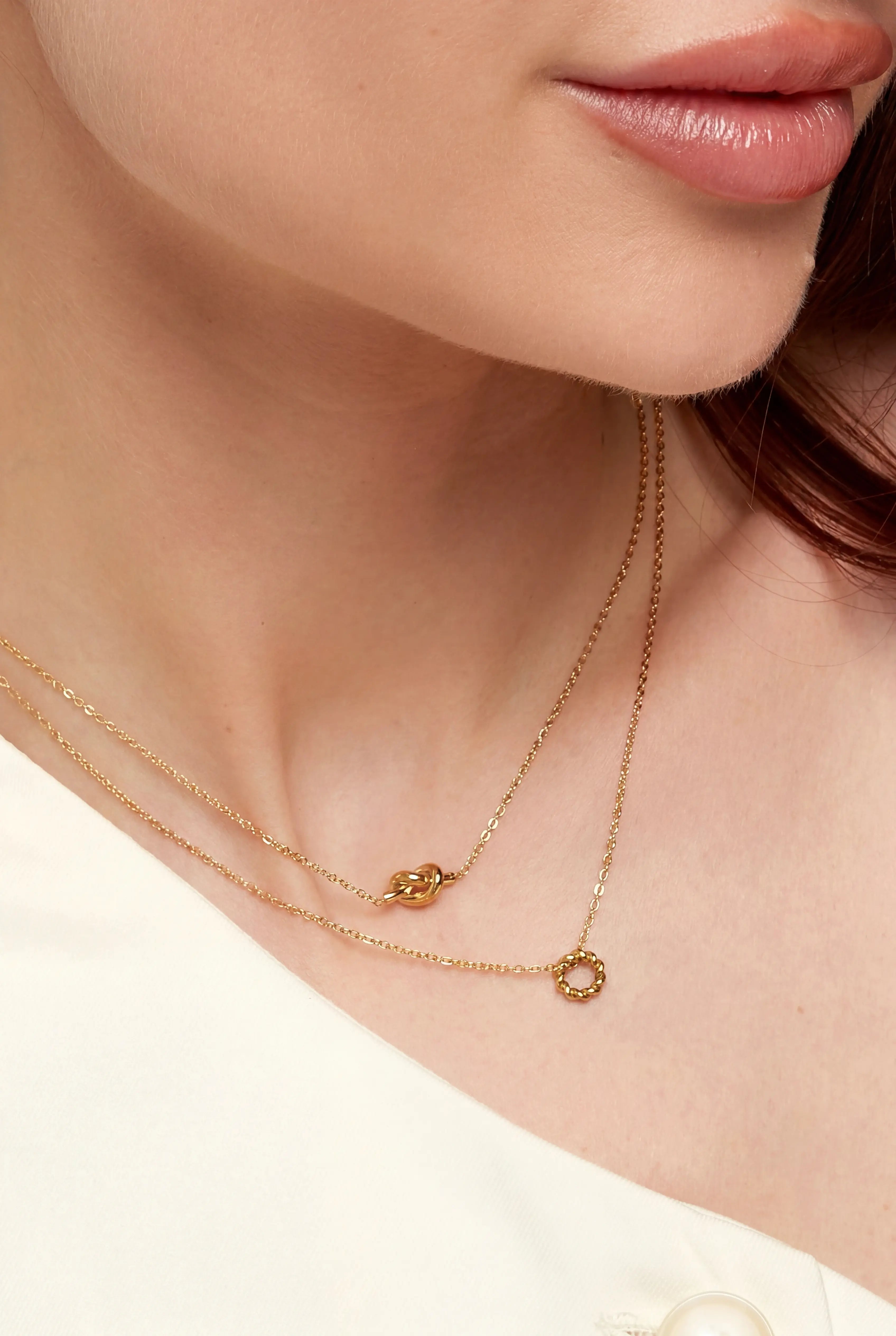 Frau trägt goldene Knoten Halskette aus vergoldetem Edelstahl von OLANA W. im minimalistischen Layering Look.