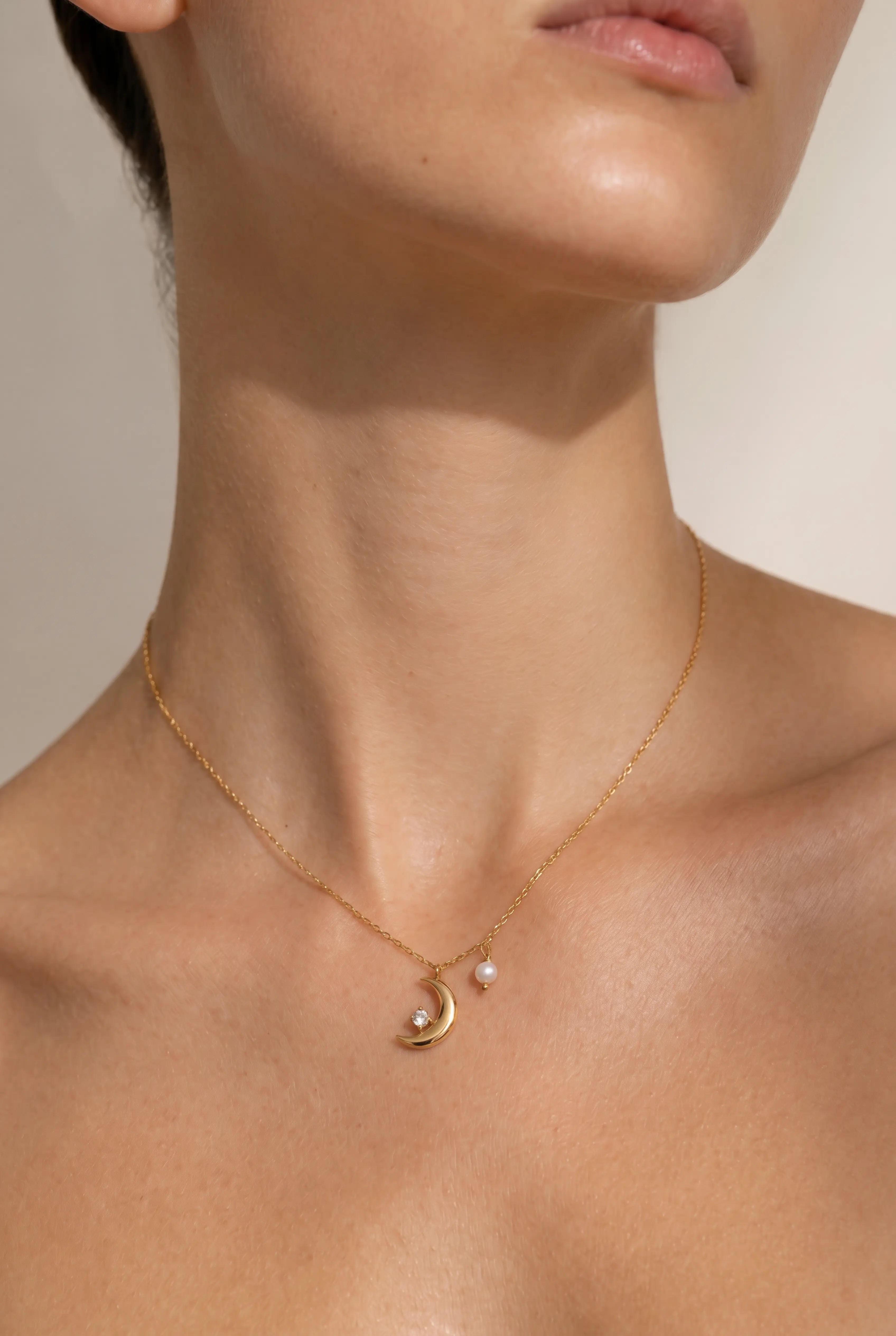 Model trägt Xena Necklace Gold mit Mond Anhänger, Perle und Strassstein